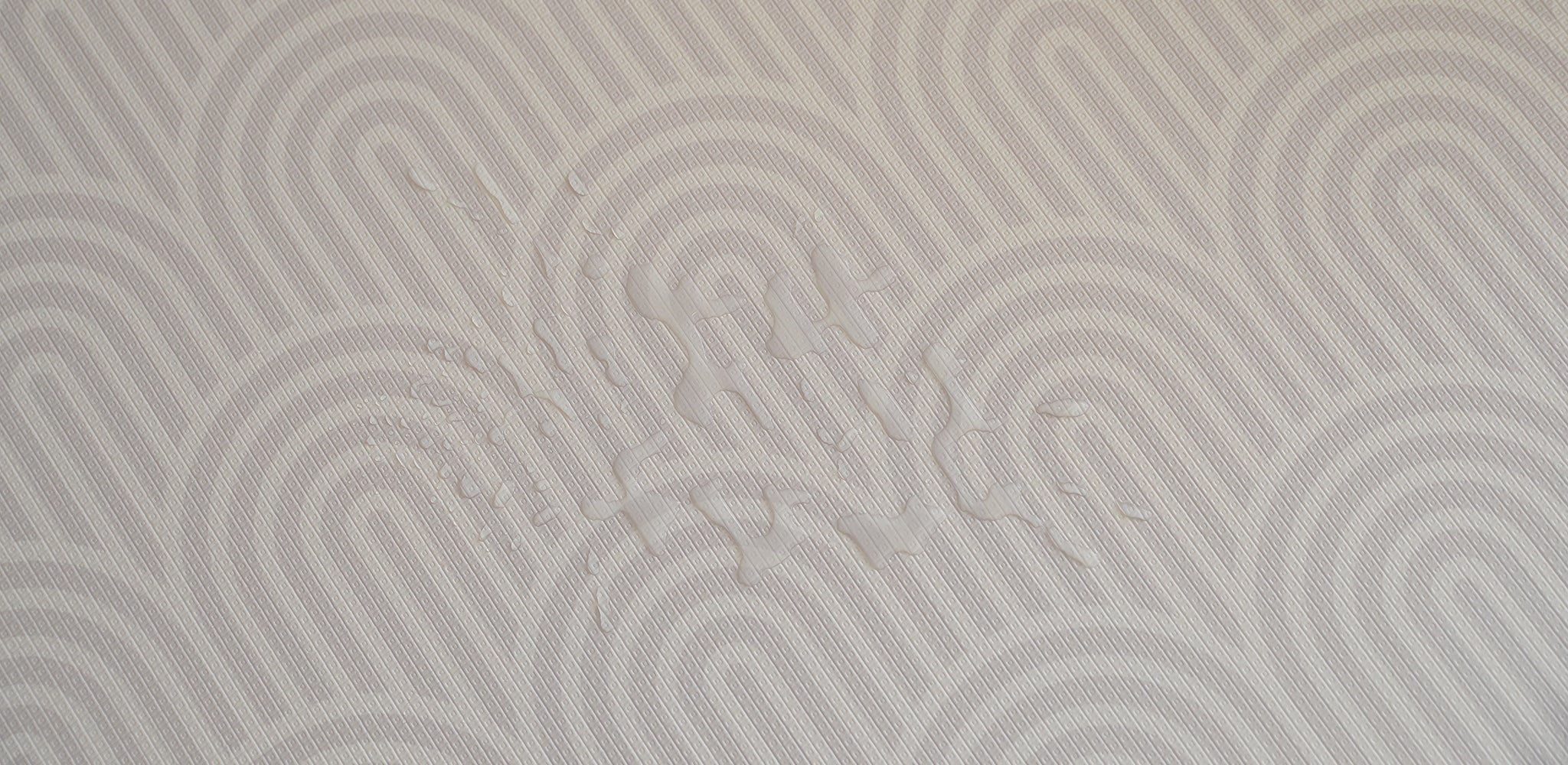 Patterned play mat with water droplets on it, showing that it is fully waterproof