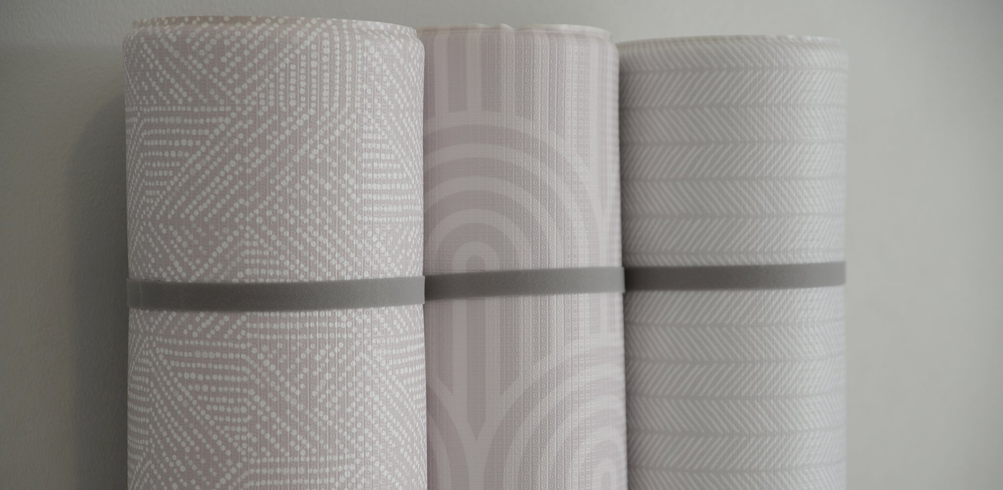 Three rolls of padded play mats with different patterns on a neutral background.