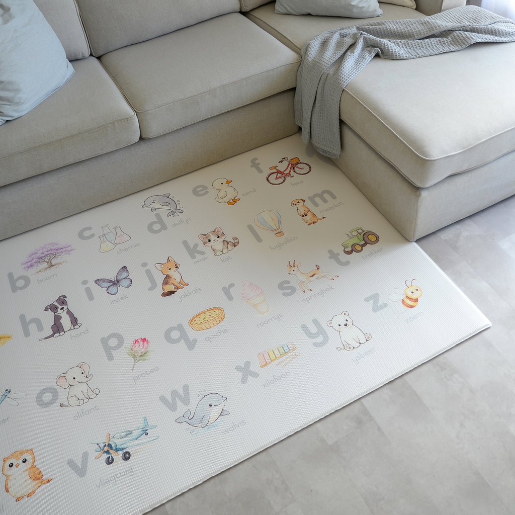 Children's play mat with alphabet and illustrations on a light-colored floor.