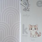 A reversible children's play mat with a alphabet design on the one side and a rainbow textured pattern on the other.