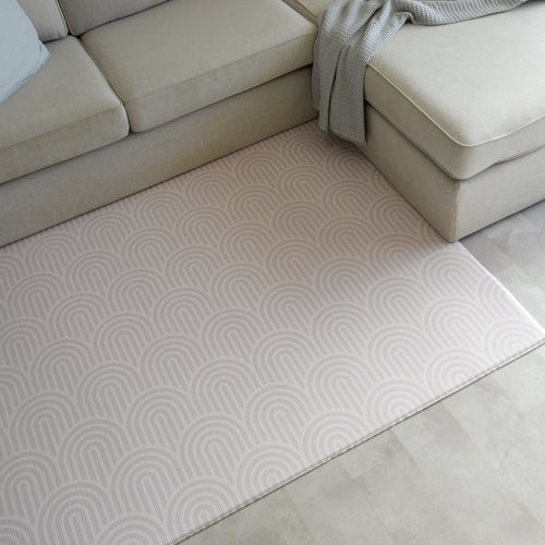 Beige sectional sofa with a rainbow patterned play mat in a living room setting