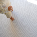 Child playing on a rainbow patterned play mat