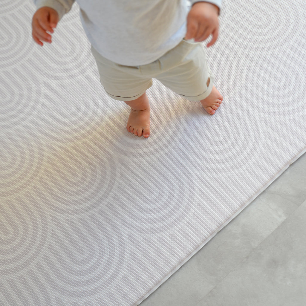 Child walking on rainbow patterned play mat