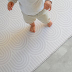 Child walking on rainbow patterned play mat