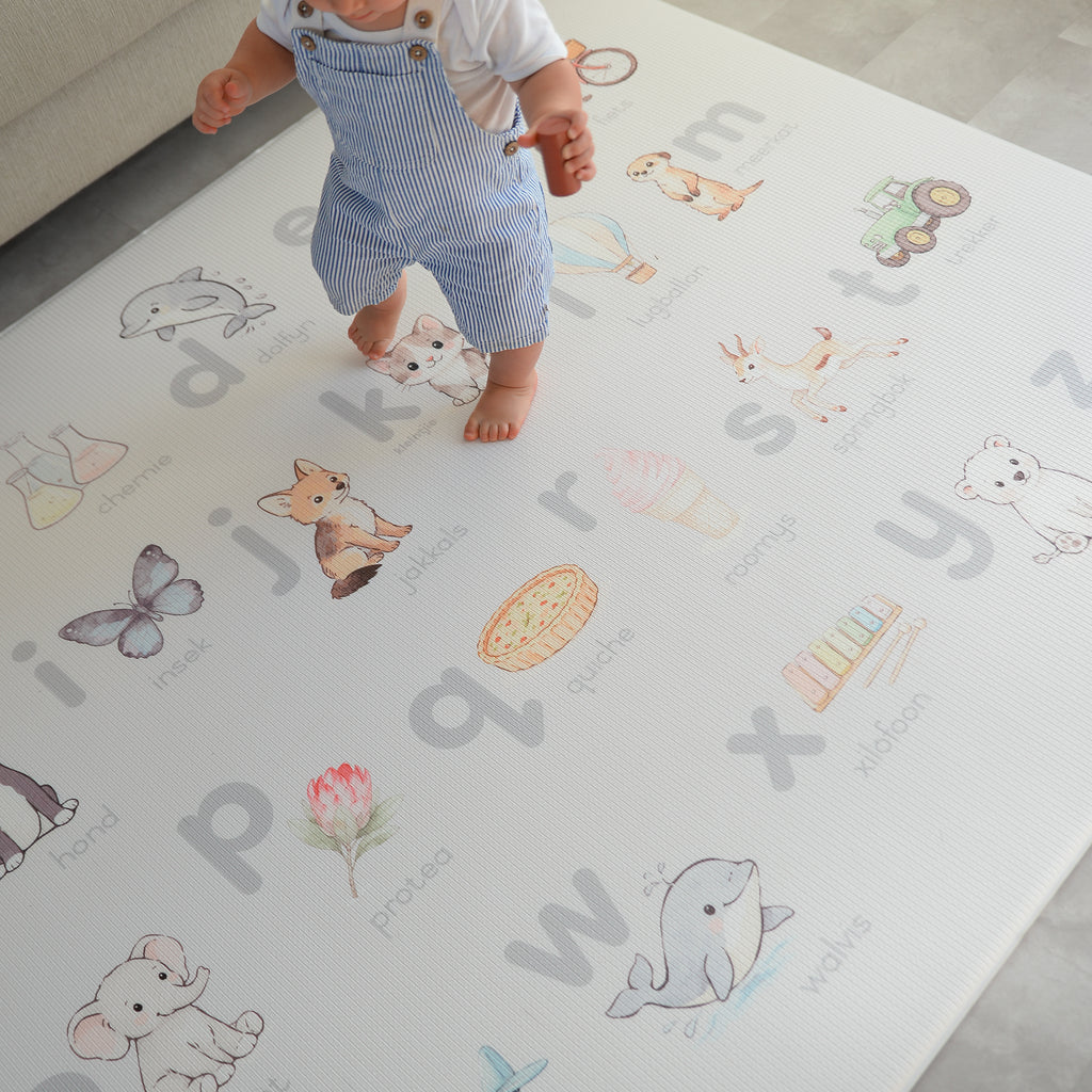 Child walking on a play mat with Afrikaans alphabet and animal illustrations