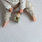 Child playing with a wooden toy on a textured play mat