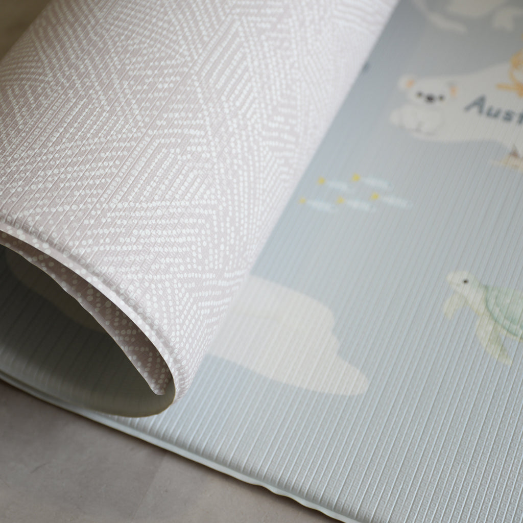 Close-up of a reversible play mat with a beige pattern on the one side, and a world map on the other.
