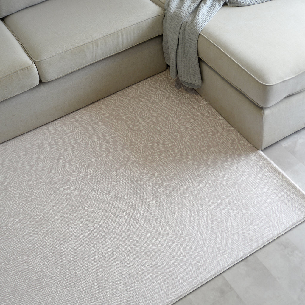 Beige sectional sofa with a modern neutral play mat in a living room setting