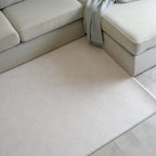 Beige sectional sofa with a modern neutral play mat in a living room setting