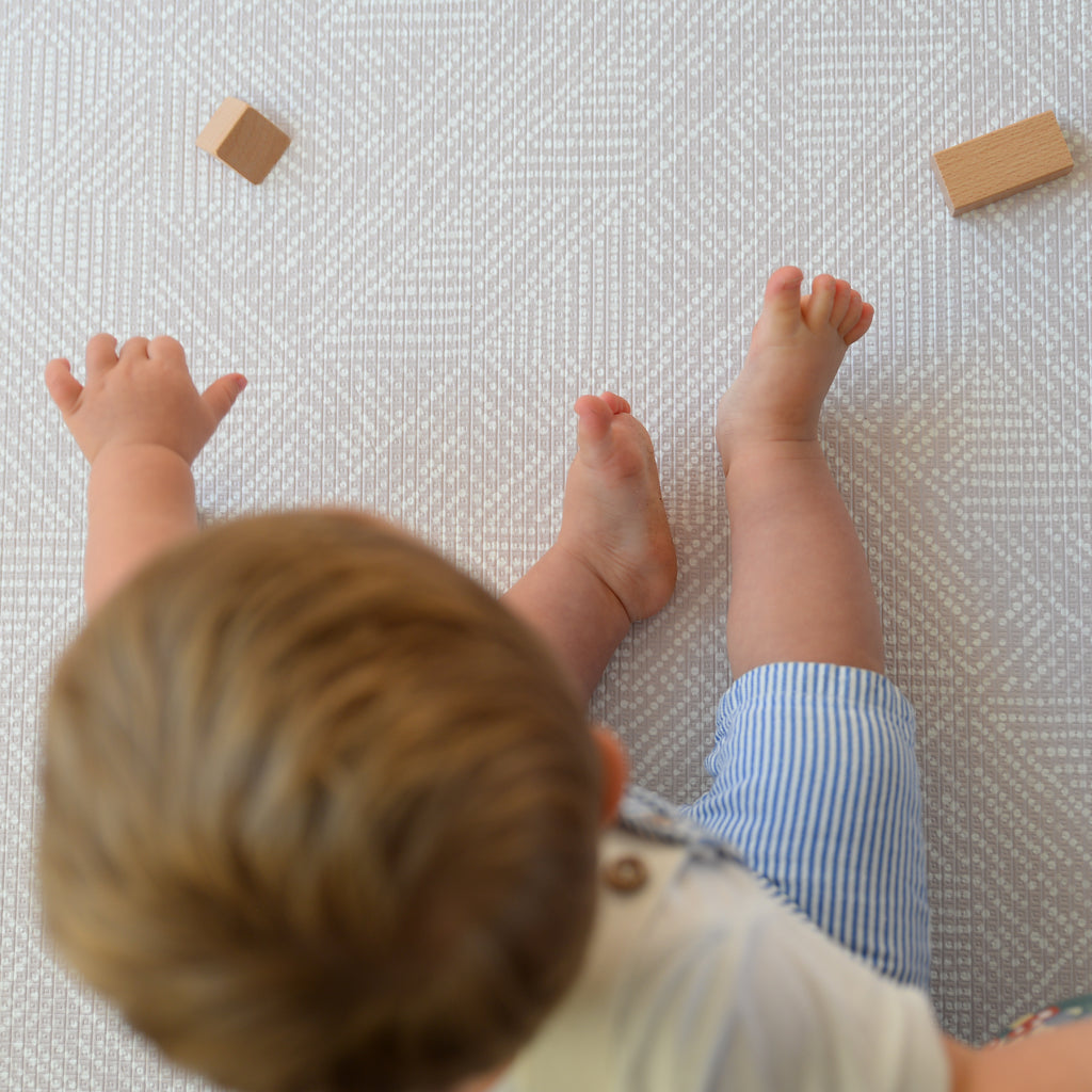 Child playing on a textured play mat