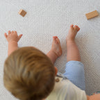 Child playing on a textured play mat