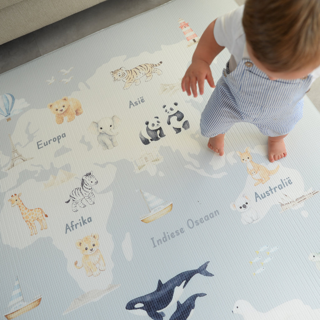 Child playing on a world map play mat with animal illustrations