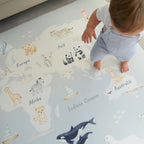 Child playing on a world map play mat with animal illustrations
