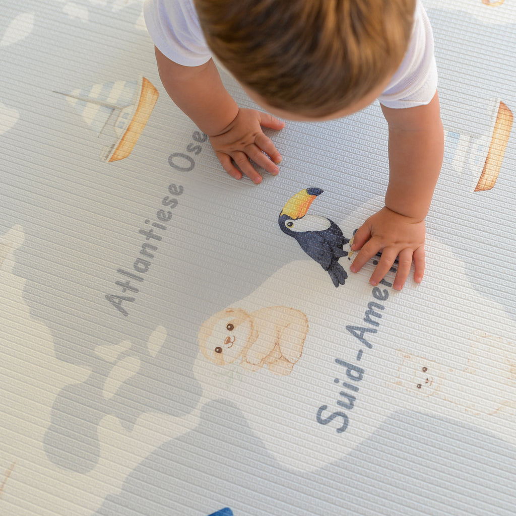 Child playing on a educational play mat with animal illustrations