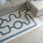 Playful play mat with road design on a light-colored floor next to a beige sofa.