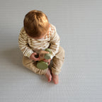 Child playing with wooden toys on a herringbone patterned play mat