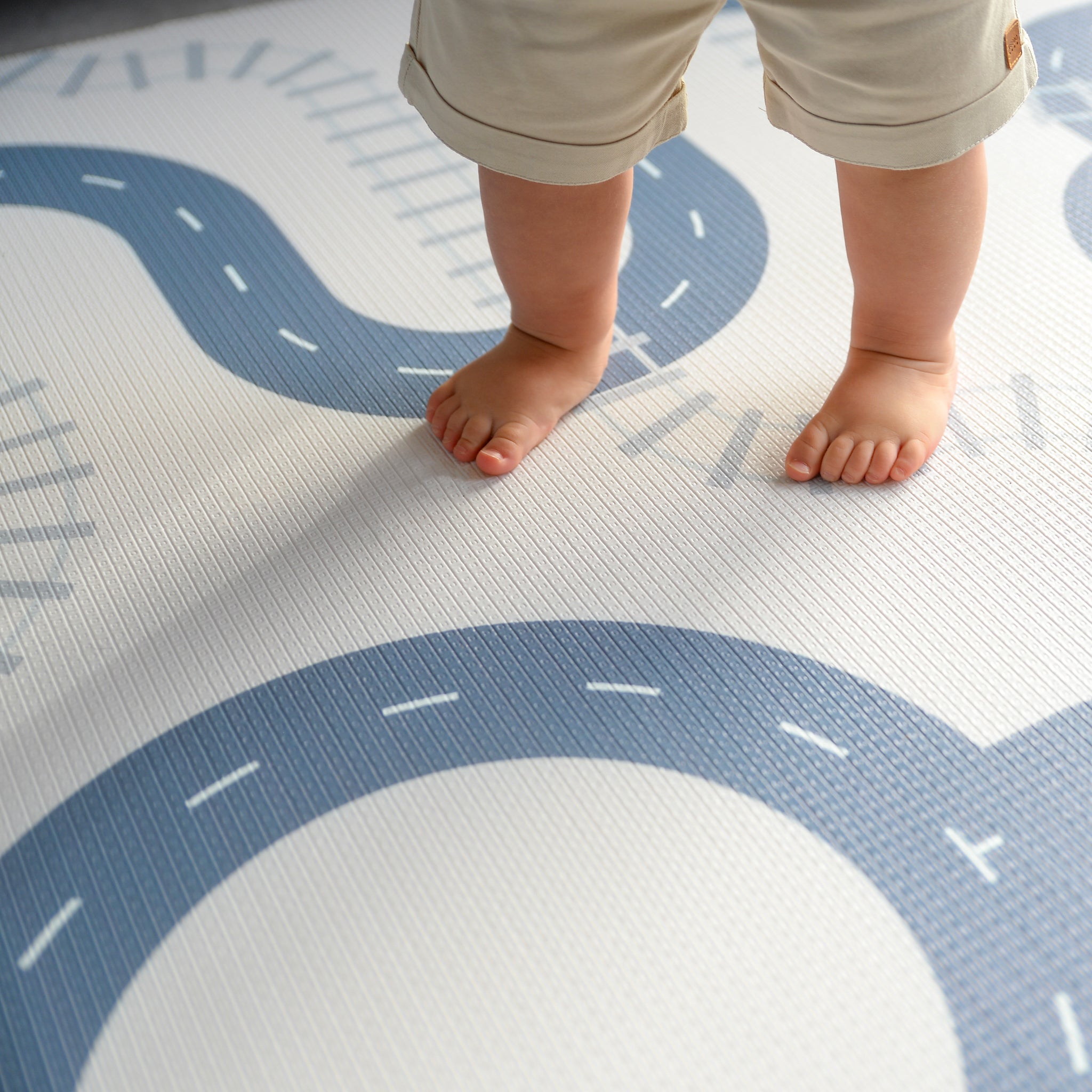 Children's feet standing on a play mat with road designs.