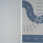 A reversible children's play mat with a road design on the one side and a herringbone textured pattern on the other.
