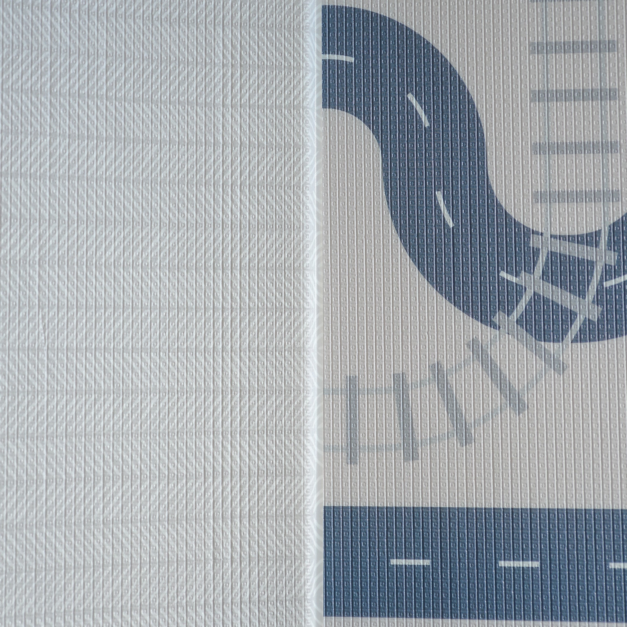 A reversible children's play mat with a road design on the one side and a herringbone textured pattern on the other.