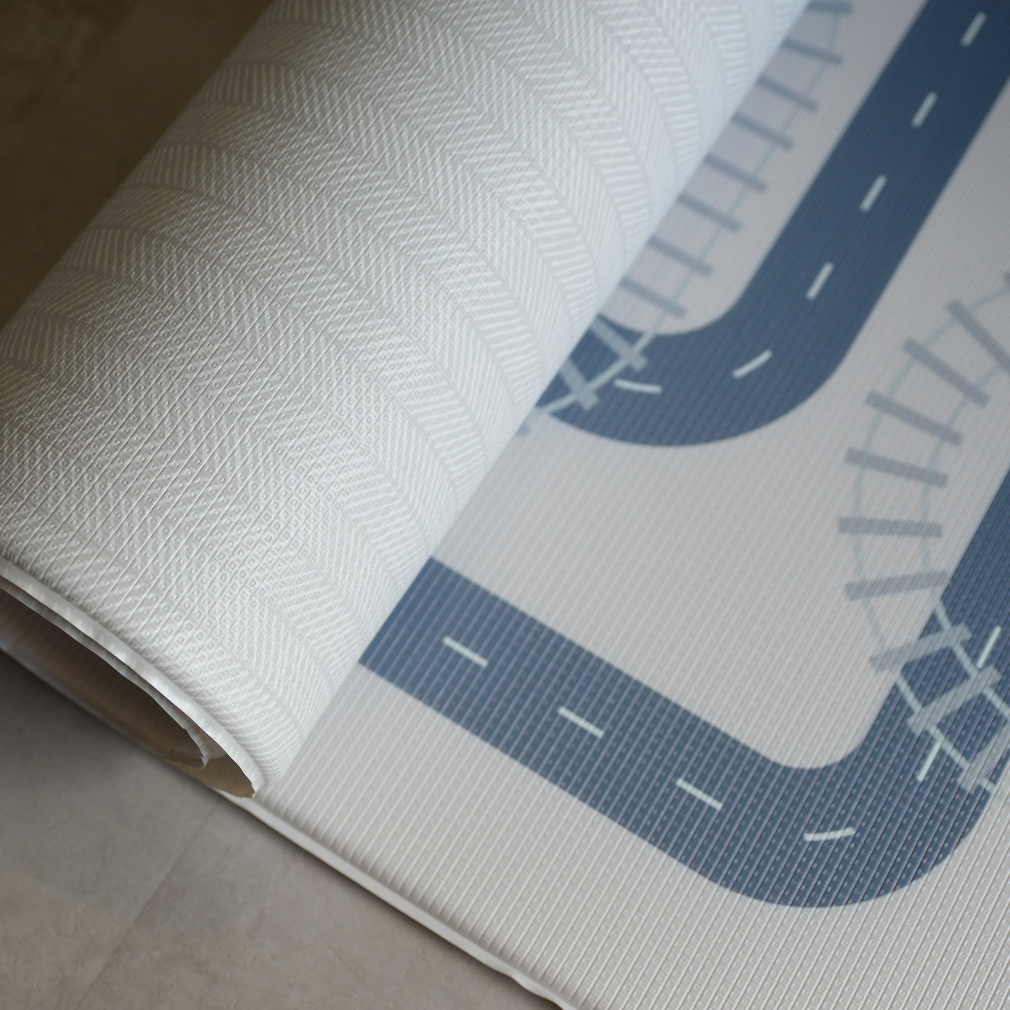 Reversible foam play mat with a herringbone pattern on the one side and a road design on the other.