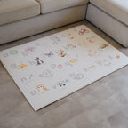 Children's alphabet play mat on a vinyl floor next to a beige sofa.