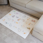 Children's alphabet play mat on a vinyl floor next to a beige sofa.