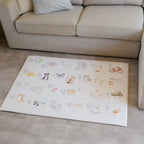 Children's alphabet play mat on a vinyl floor next to a beige sofa.