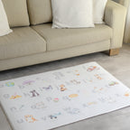 Children's play mat with Afrikaans alphabet and illustrations on a floor in a living room.