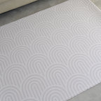 Beige rainbow patterned play mat on a gray floor
