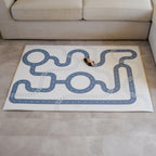 Play mat with road design on a floor in front of a beige couch