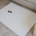 Herringbone patterned play mat on a floor with a small toy car on it