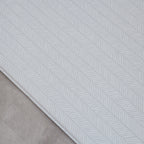 Sage play mat with a herringbone pattern on a concrete floor.