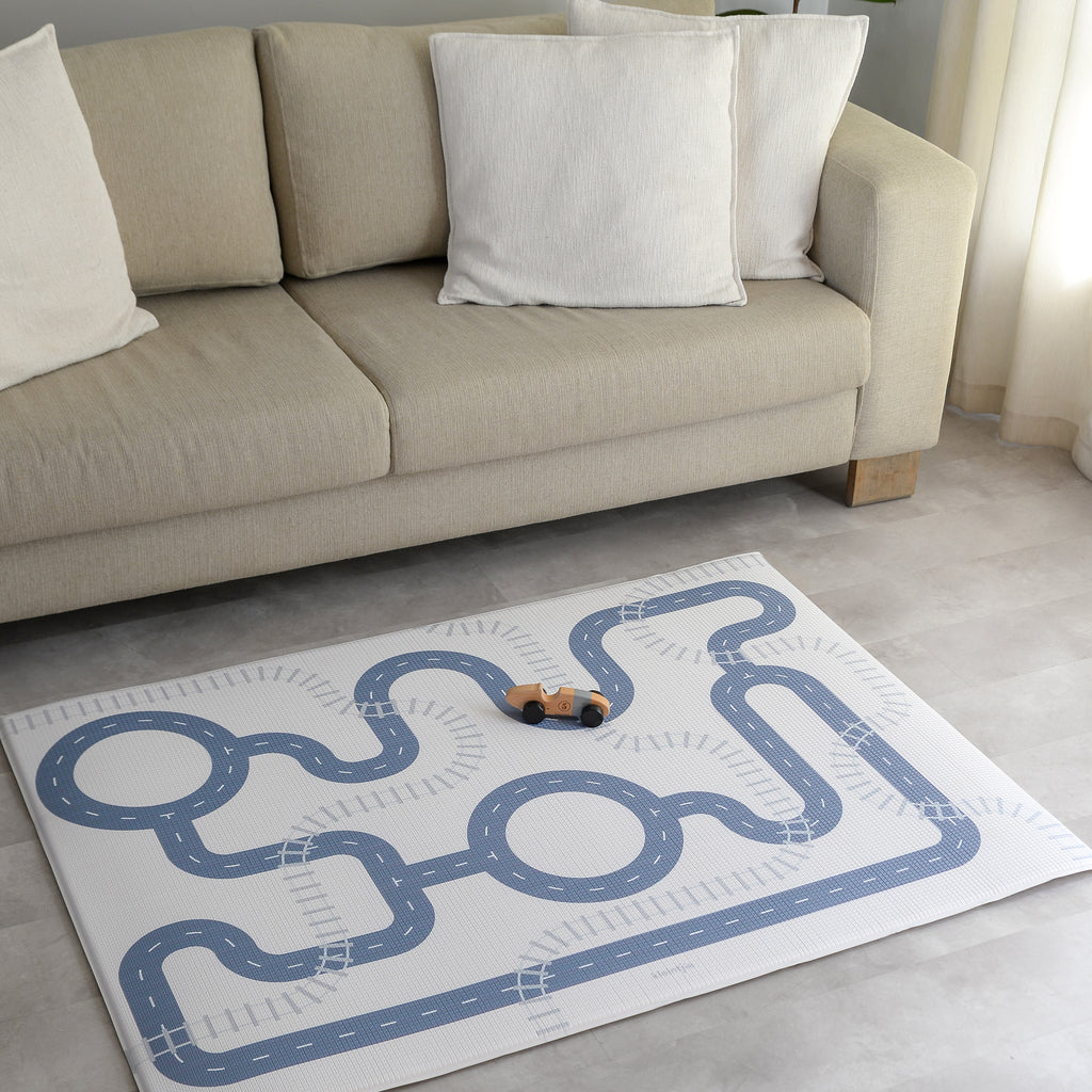 Children's play mat with road design on a floor in a living room.