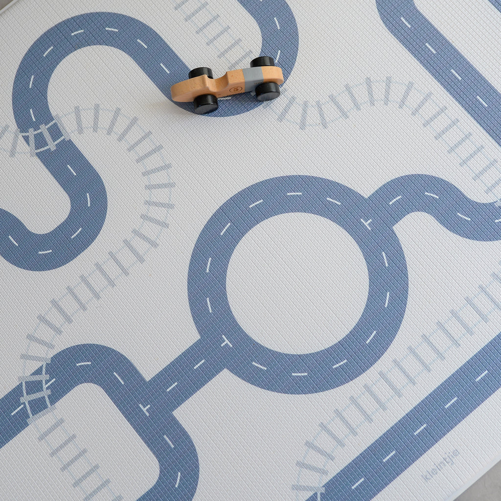 Play mat with road design and toy cars on a light gray background