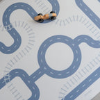 Play mat with road design and toy cars on a light gray background