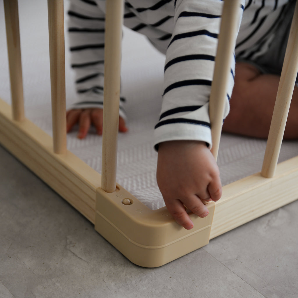 Child's hand reaching through a baby playpen with striped shirt on