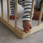 Child's hand reaching through a baby playpen with striped shirt on