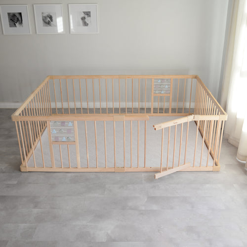 Wooden playpen and play mat in a room with light gray flooring and white walls.