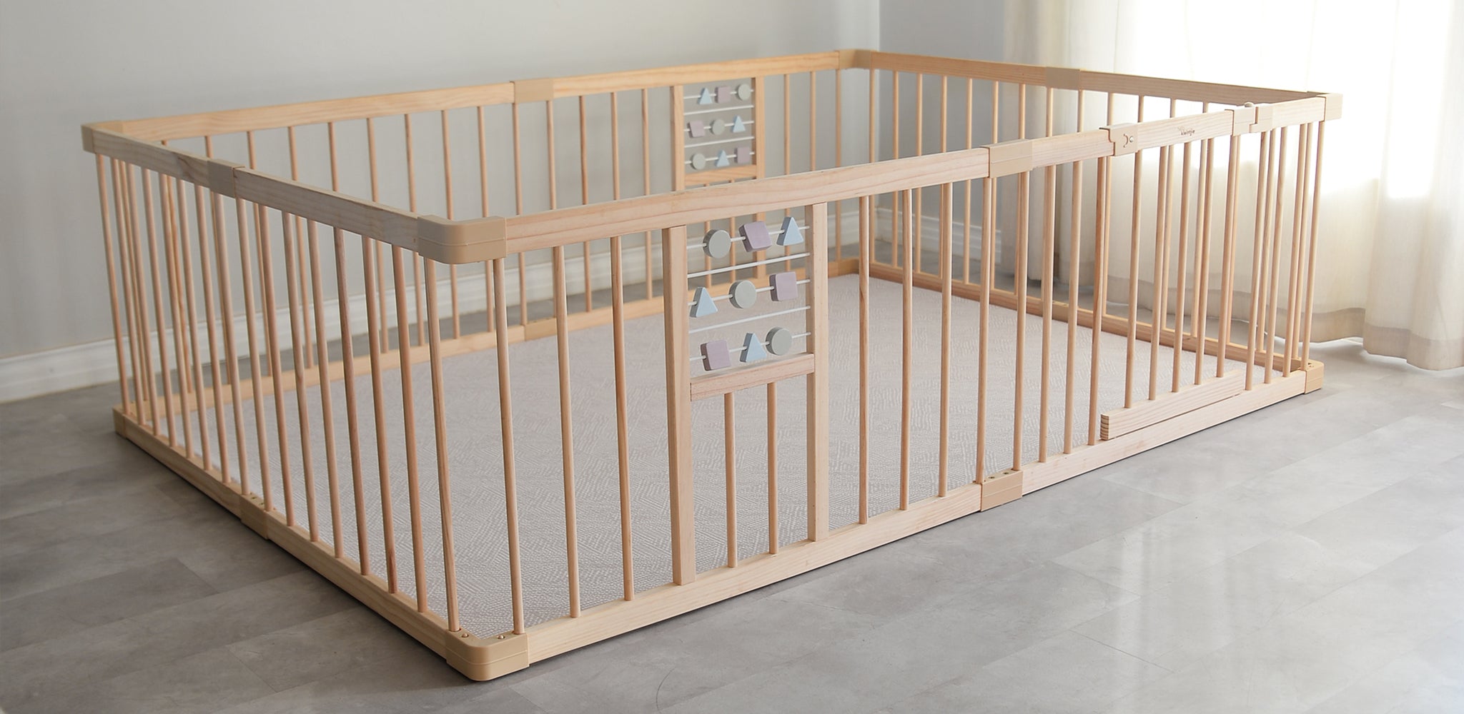 Wooden baby playpen on a grey floor with a neutral background