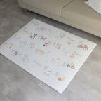 Children's play mat with Afrikaans alphabet and illustrations on a floor in a living room.