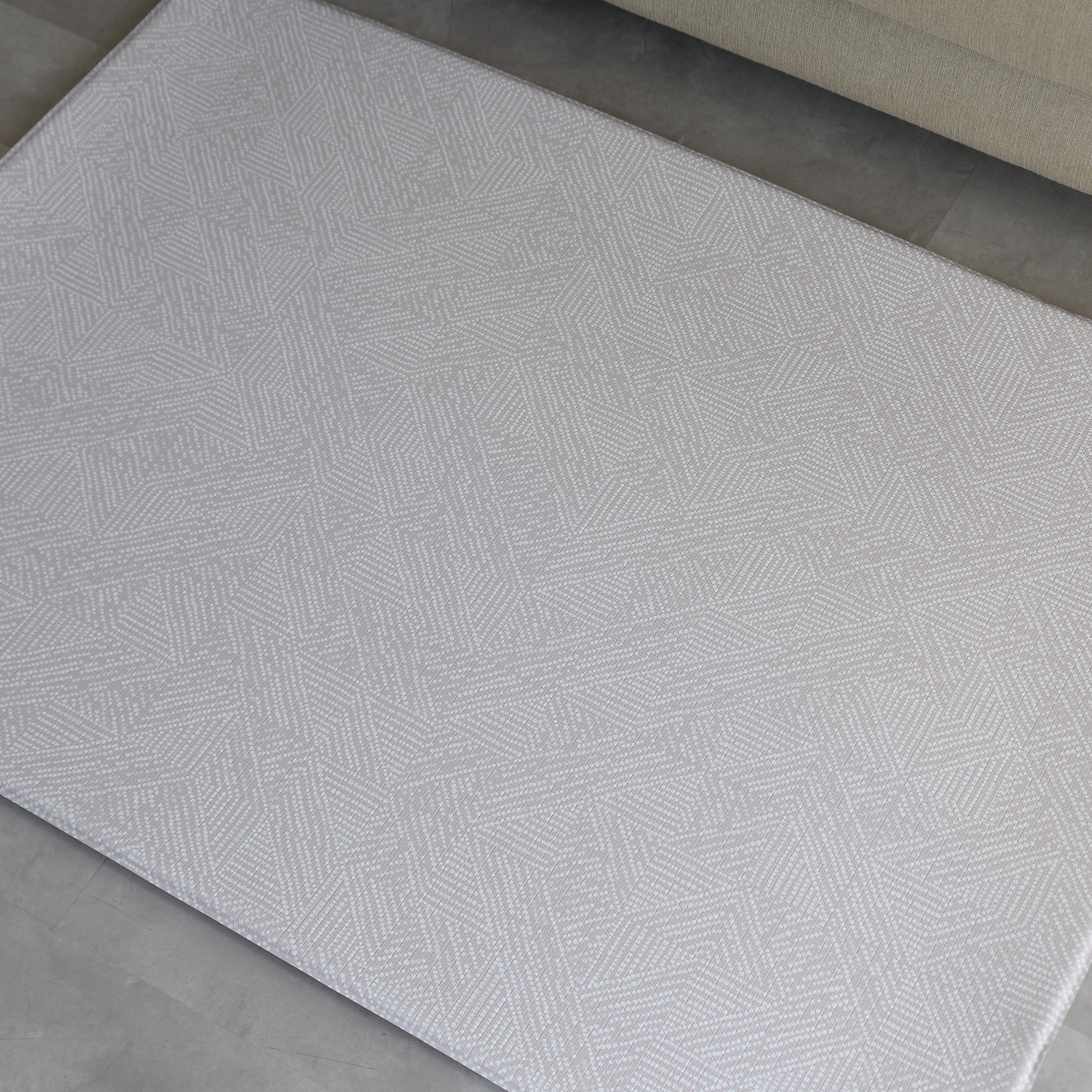 Beige dots textured play mat on a concrete floor
