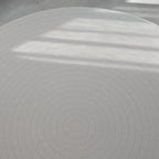 Beige play mat with a herringbone pattern on a concrete floor.