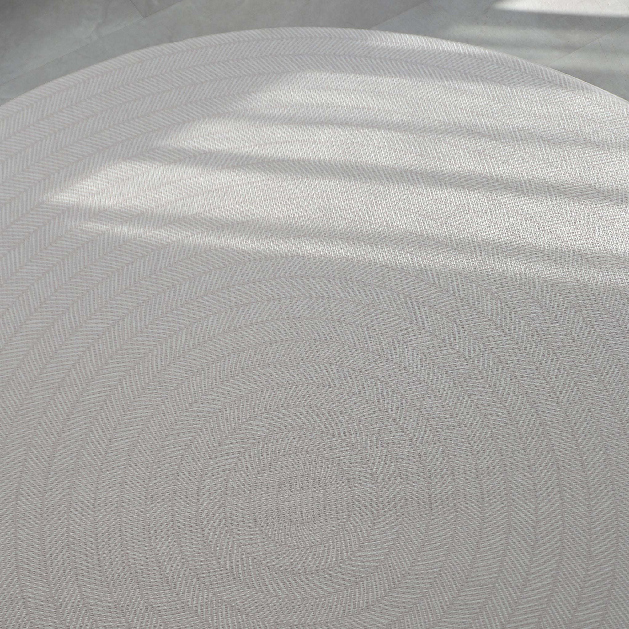 Beige play mat with a herringbone pattern on a concrete floor.