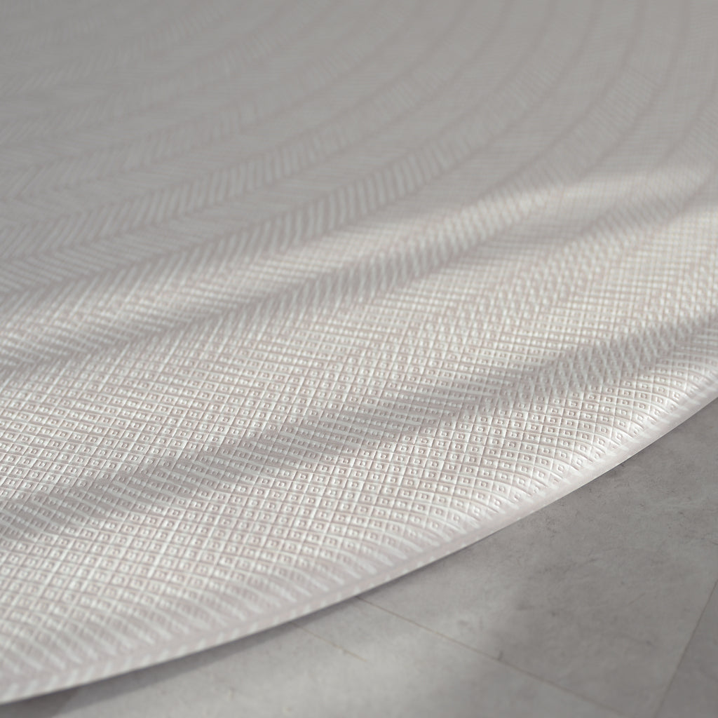 Beige play mat with a herringbone pattern on a concrete floor.