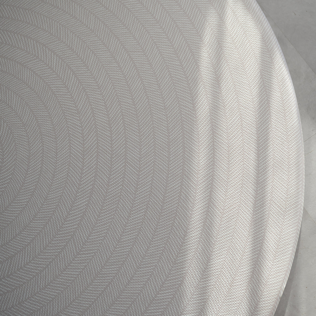 Beige play mat with a herringbone pattern on a concrete floor.