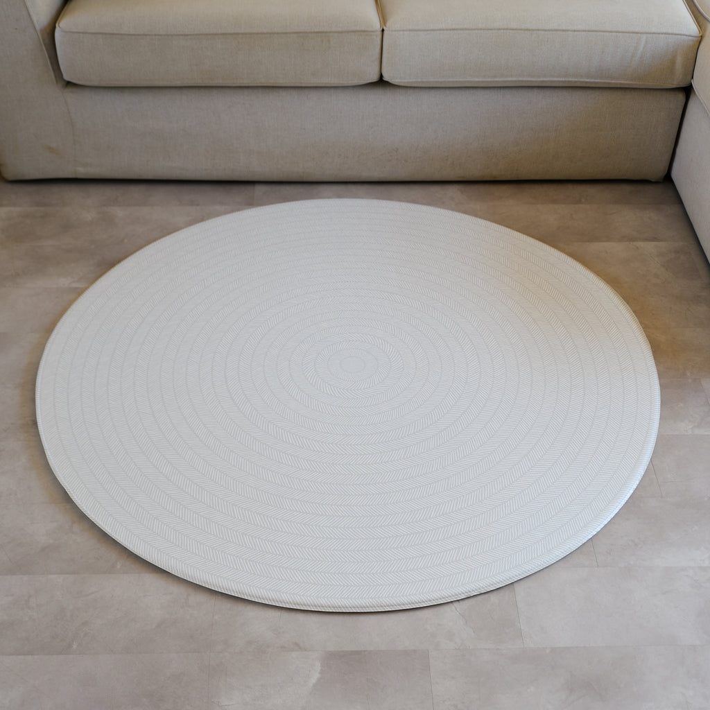 Sage play mat with a herringbone pattern on a concrete floor.