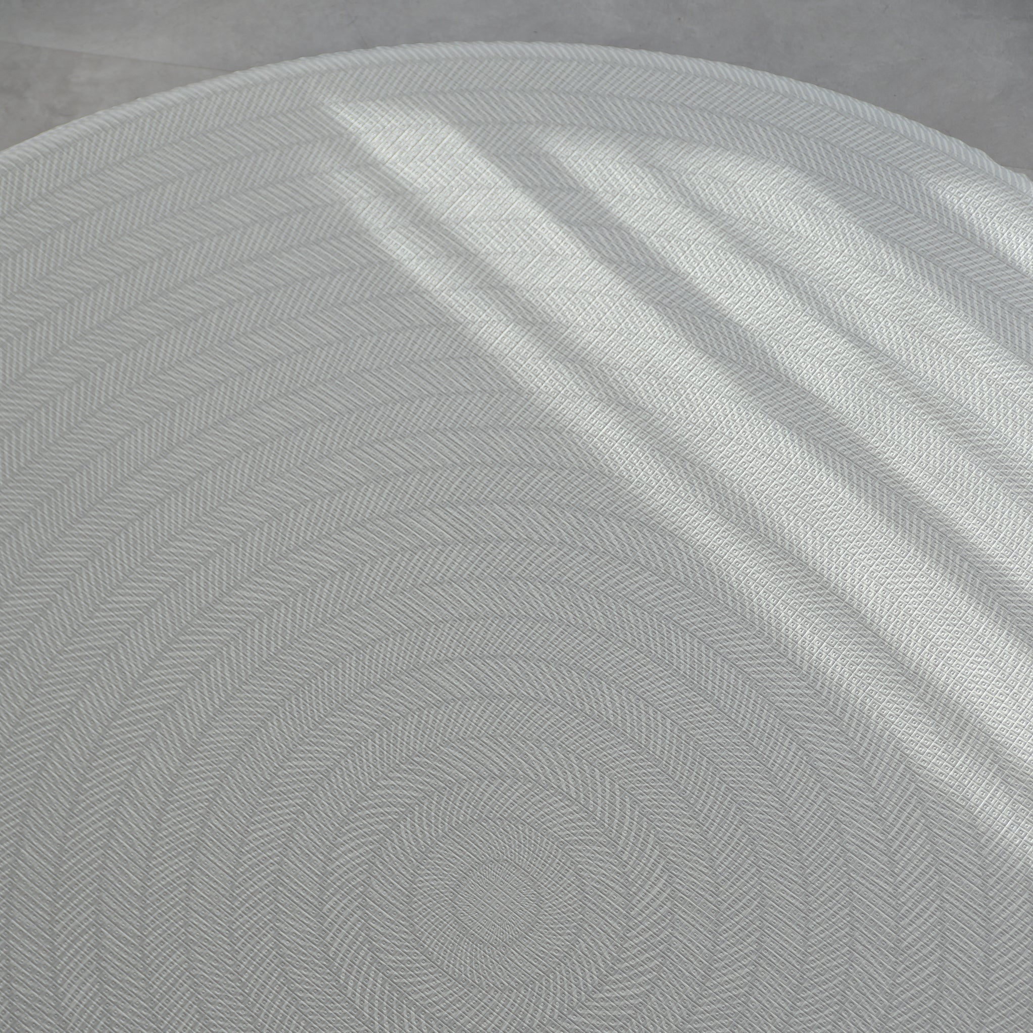 Sage play mat with a herringbone pattern on a concrete floor.